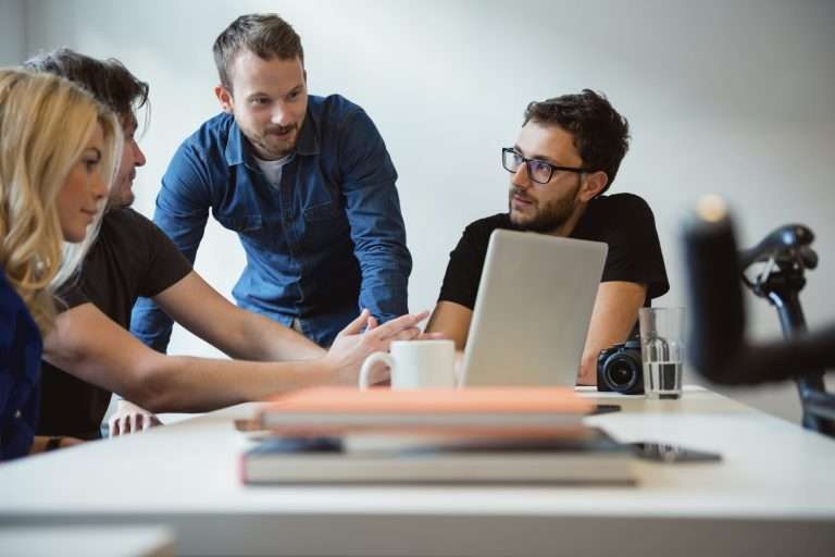 Grupo de pessoas reunidas em uma mesa de trabalho discutindo estratégias com notebook aberto, ilustrando o planejamento e aproveitamento de benefícios fiscais por empresas.