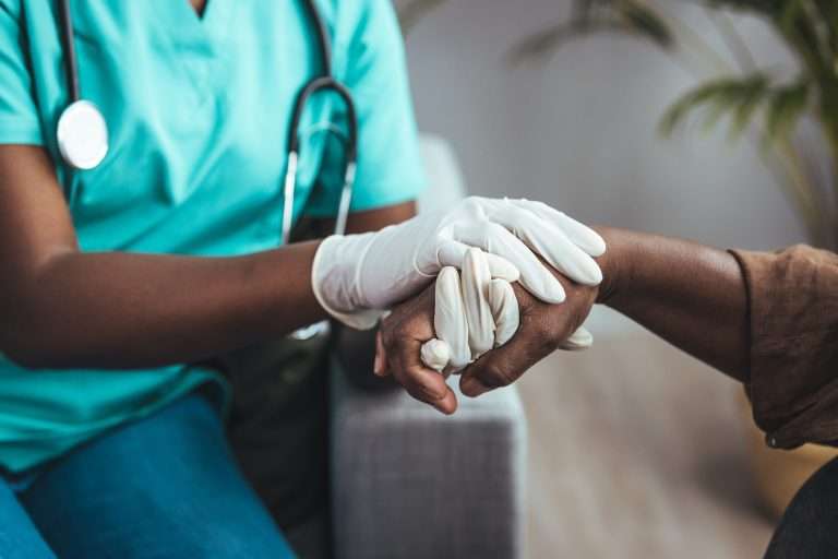 Médica segurando a mão de um paciente, mostrando como a filantropia e a saúde são aliadas.