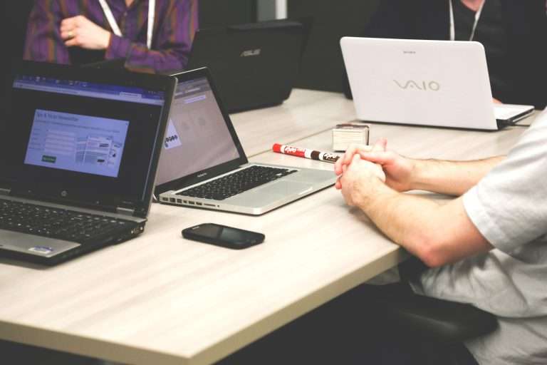 Pessoas reunidas em torno de uma mesa com notebooks e anotações, em ambiente corporativo, simbolizando reuniões estratégicas para definir ações de responsabilidade social corporativa nas empresas.