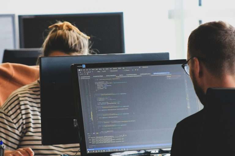 Pessoas trabalhando em computadores em um ambiente de escritório ou treinamento de tecnologia.
