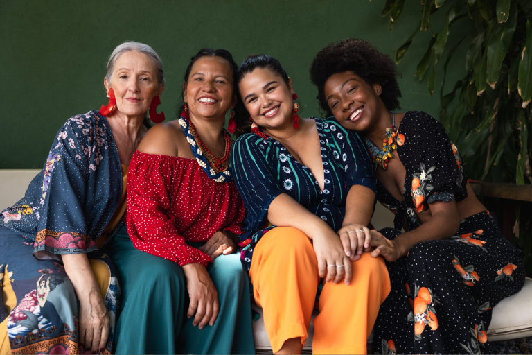 Grupo de quatro mulheres sorrindo juntas.