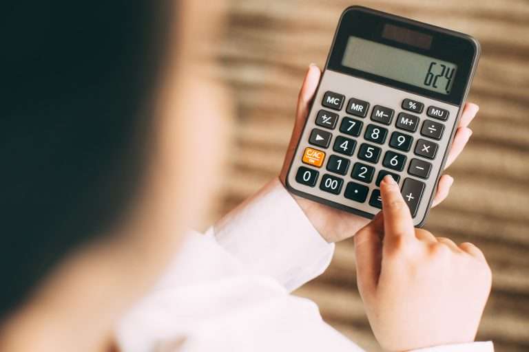 Pessoa fazendo cálculos de informações financeiras com calculadora.