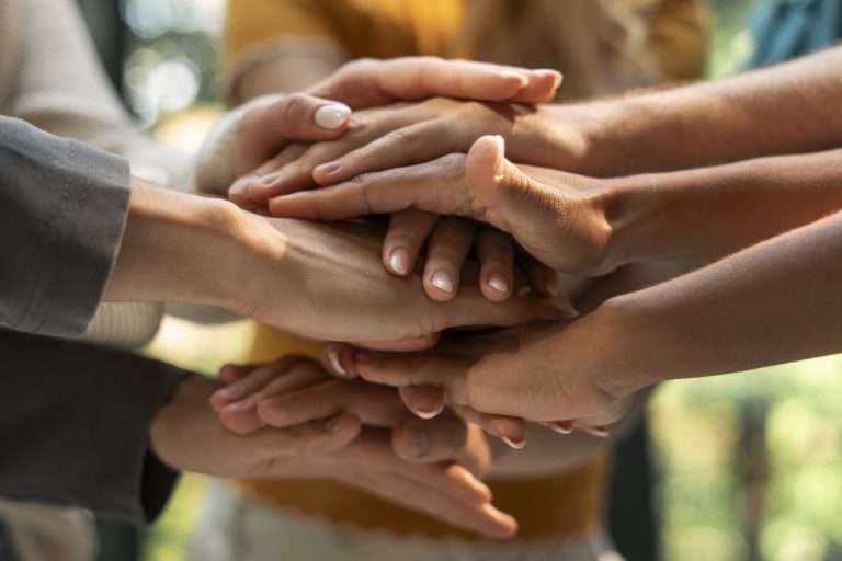 Diversas mãos empilhadas em gesto de união e colaboração.