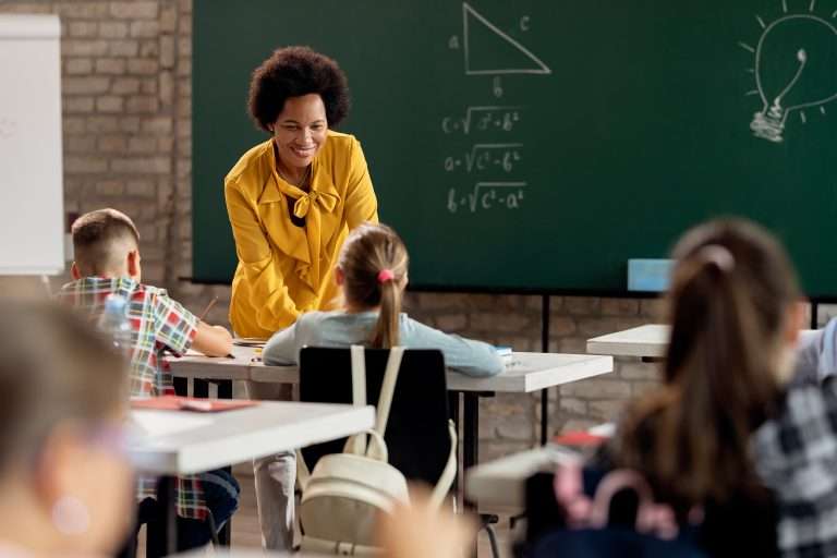 Professora interagindo com crianças em sala de aula.